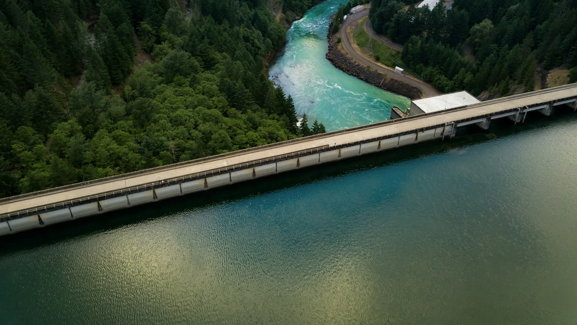 Hydropower headrace channel running alongside a river through a forested valley